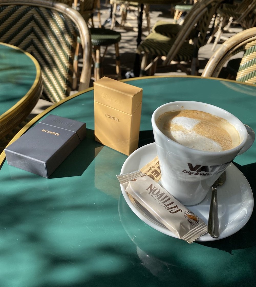 Étuis ÉCRAN My Choice et Essentiel posés sur une table de café à Paris, à côté d'un cappuccino